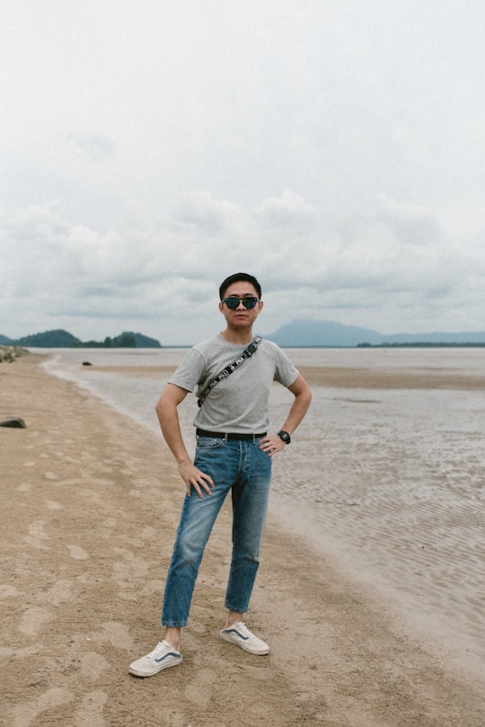 woman in white shirt and blue denim jeans standing on beach shore during daytime in Kuching Malaysia