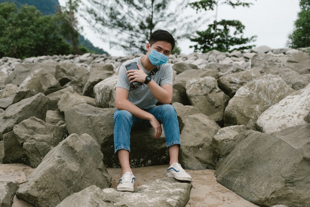 boy in black t-shirt and blue denim shorts sitting on rock during daytime