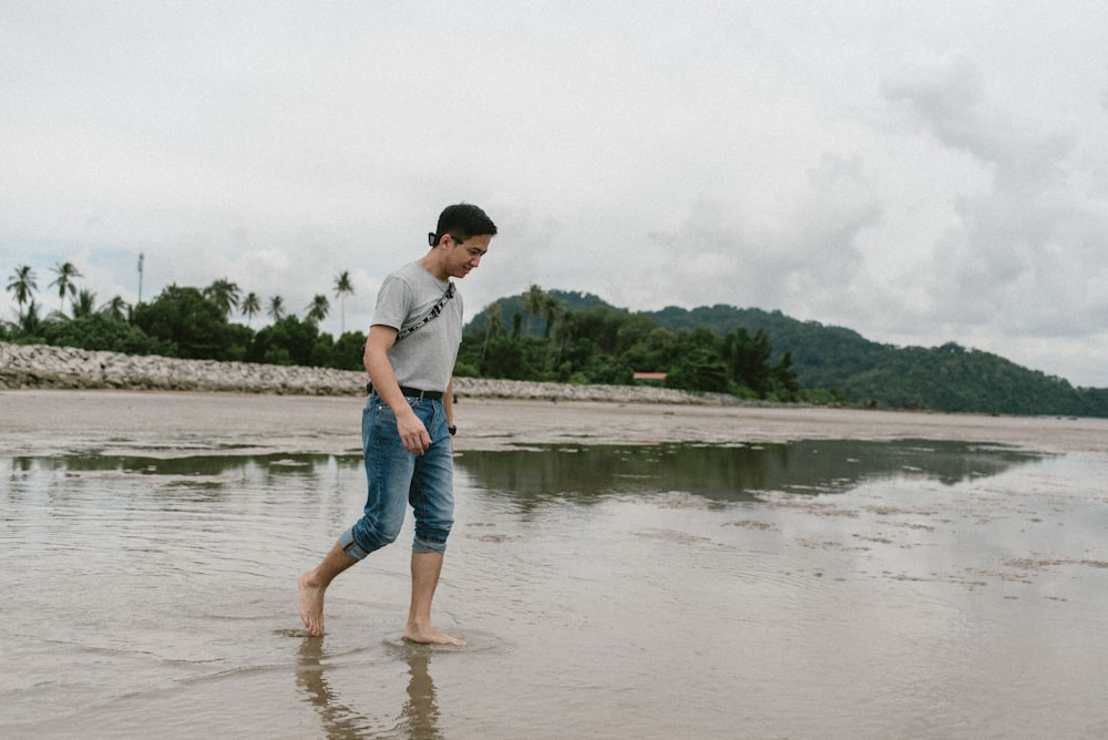 man in white t-shirt and blue denim shorts standing on water during daytime