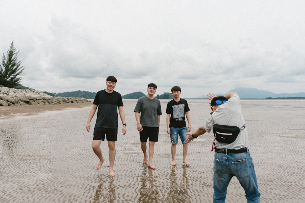 3 men and 2 women standing on beach during daytime