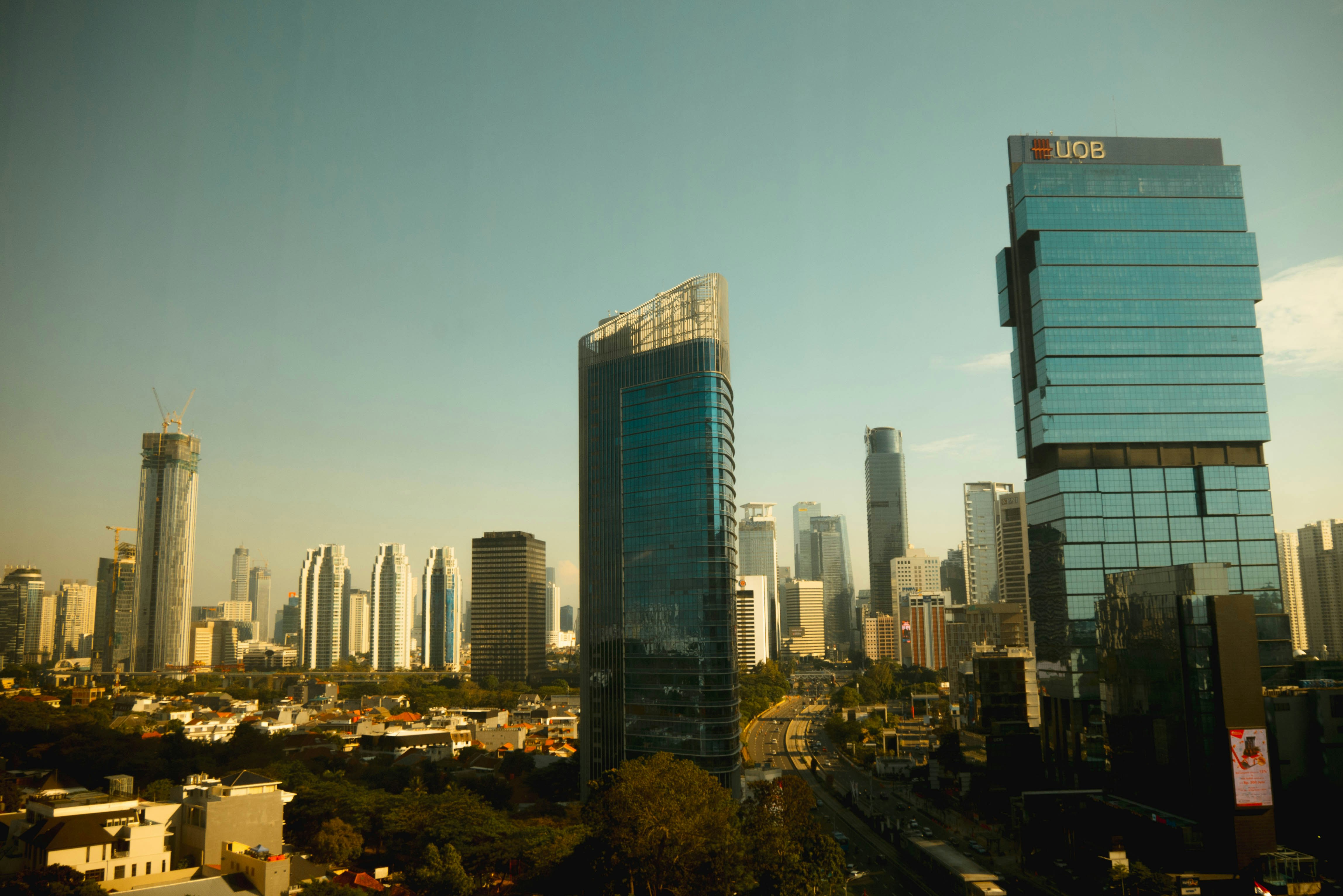 city skyline under blue sky during daytime, Jakarta, 4 pm.