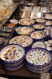 A collection of hand-crafted plates with playful patterns and bright colors on a linen tablecloth.
