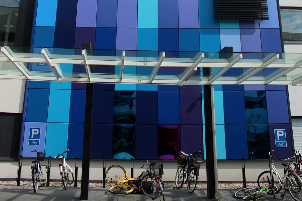 Biciclette da città bianche e nere parcheggiate accanto all'edificio blu e bianco durante il giorno