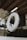A lifebuoy is hanging from a rope in an indoor setting with wooden beams and glass panels. The text 'SAUVETEURS EN MER GF SN SM' is visible on the lifebuoy. The background includes framed pictures and dark furniture.