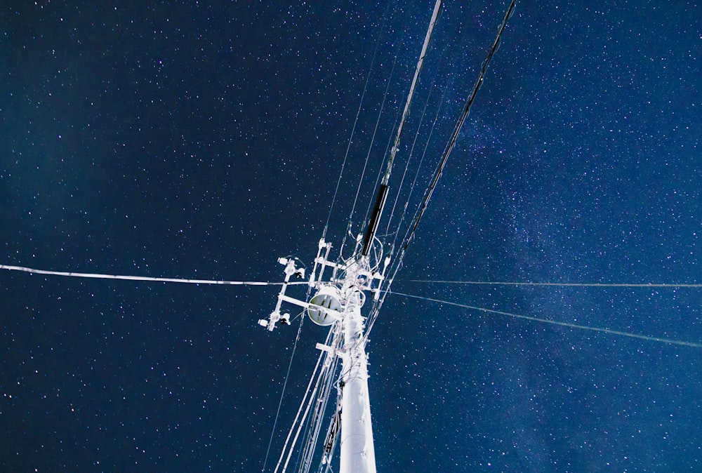 Poste eléctrico blanco bajo el cielo azul durante la noche