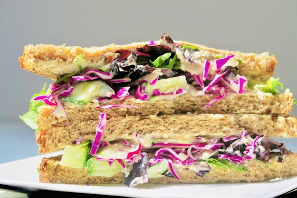 A stacked sandwich filled with colorful fresh ingredients and melted cheese on a wooden table