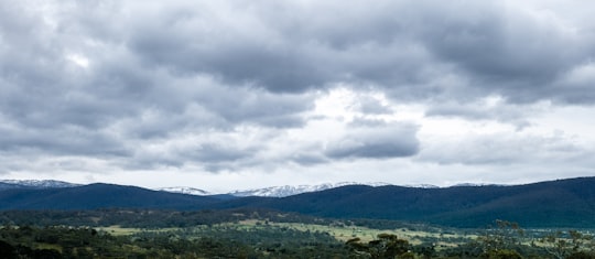 green trees and mountains under white clouds during daytime in Jindabyne NSW Australia