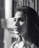 A serene portrait of a woman admiring a delicate pair of earrings, sunlight casting soft shadows.