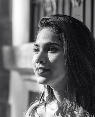 A serene portrait of a woman admiring a delicate pair of earrings, sunlight casting soft shadows.