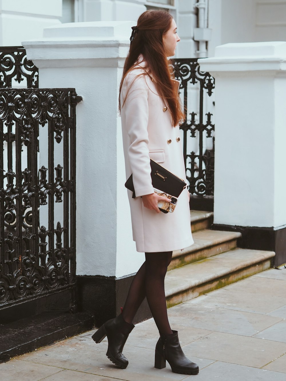 woman in white blazer and black skirt standing on white concrete staircase