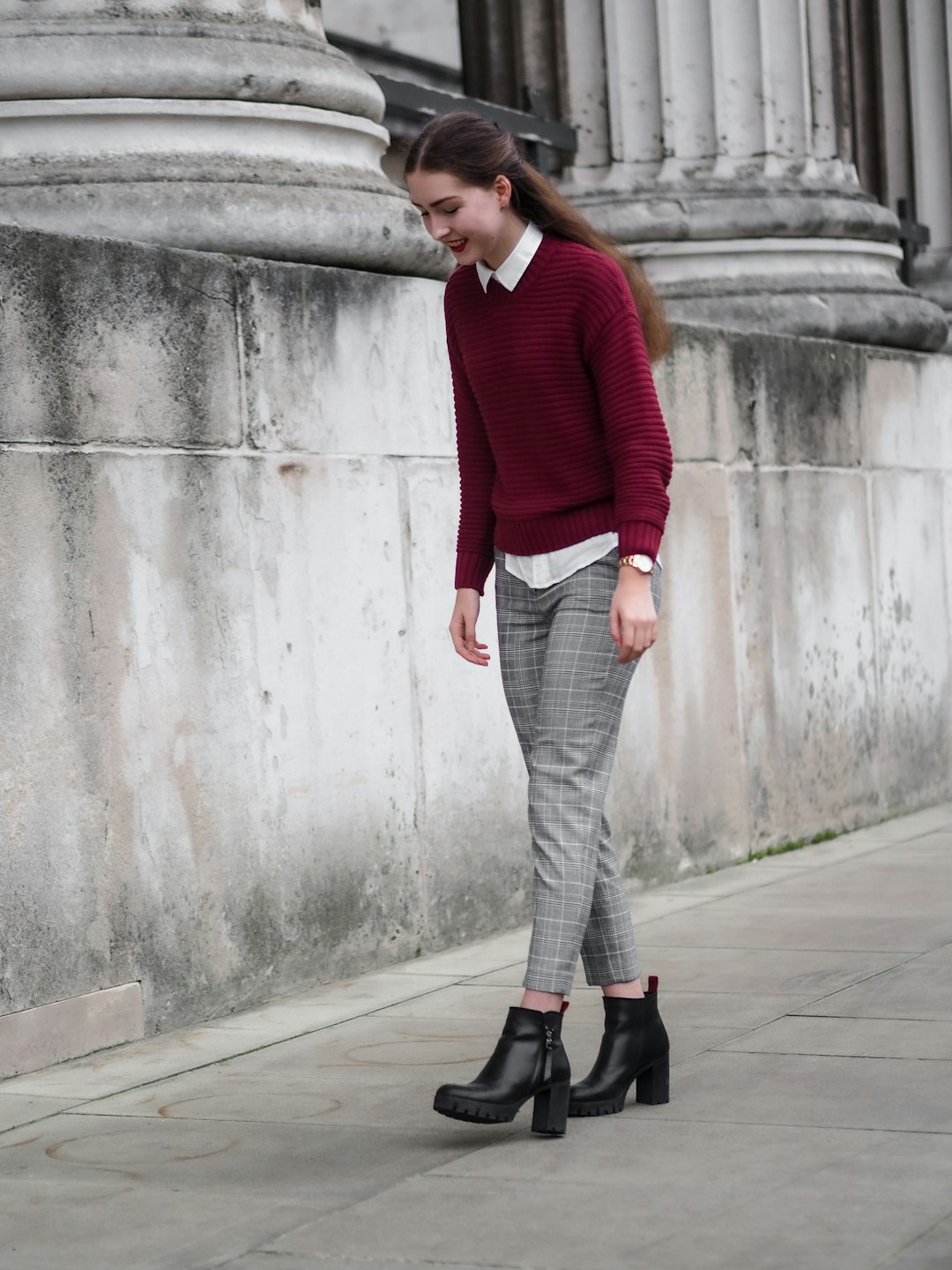 woman in red sweater and gray pants standing on sidewalk during daytime