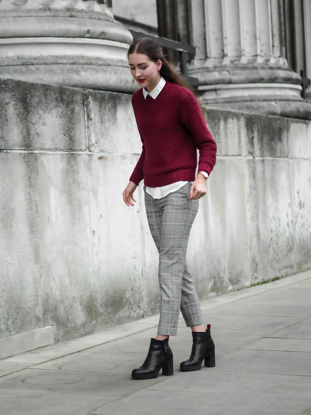 man in red sweater and gray pants standing beside gray concrete wall during daytime