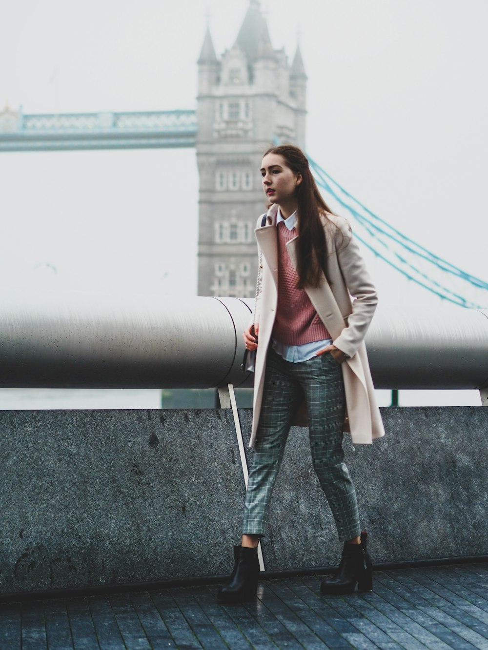 woman in gray blazer and black pants standing beside gray metal pipe