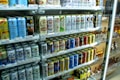 A refrigerated display stocked with a variety of canned beverages, predominantly beer. The cans display colorful designs and different brands, with signs and price tags visible. The shelves are neatly arranged, showcasing a wide selection of drinks for sale.