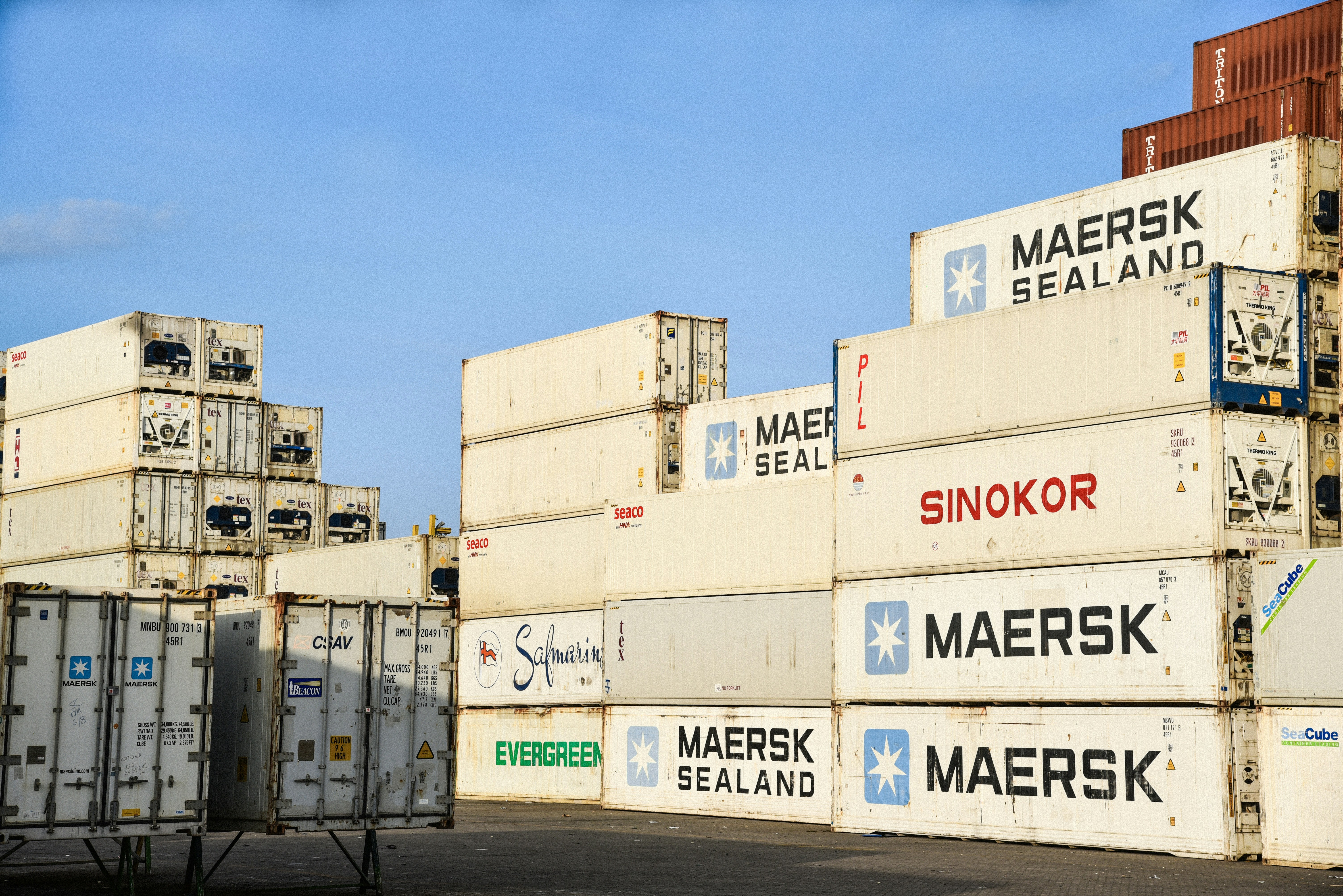 Conteneurs maritimes empilés dans une cour de stockage industrielle.