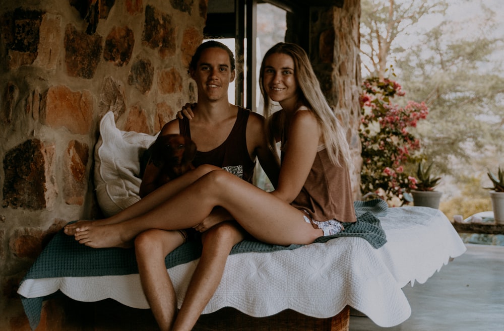 2 women in black tank top sitting on bed