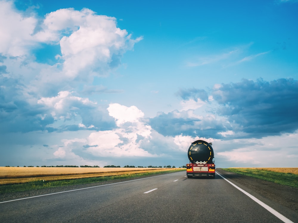 black car on road under blue sky and white clouds during daytime