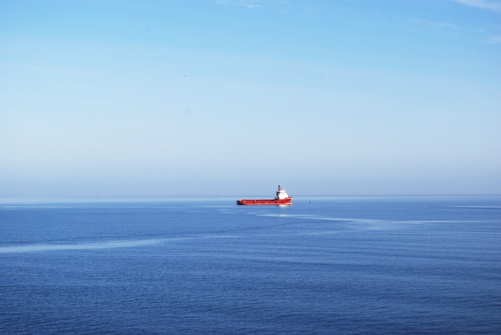 red boat on sea under blue sky during daytime