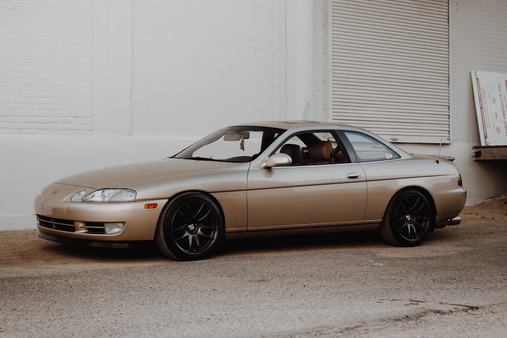 gold mercedes benz coupe parked beside white wall