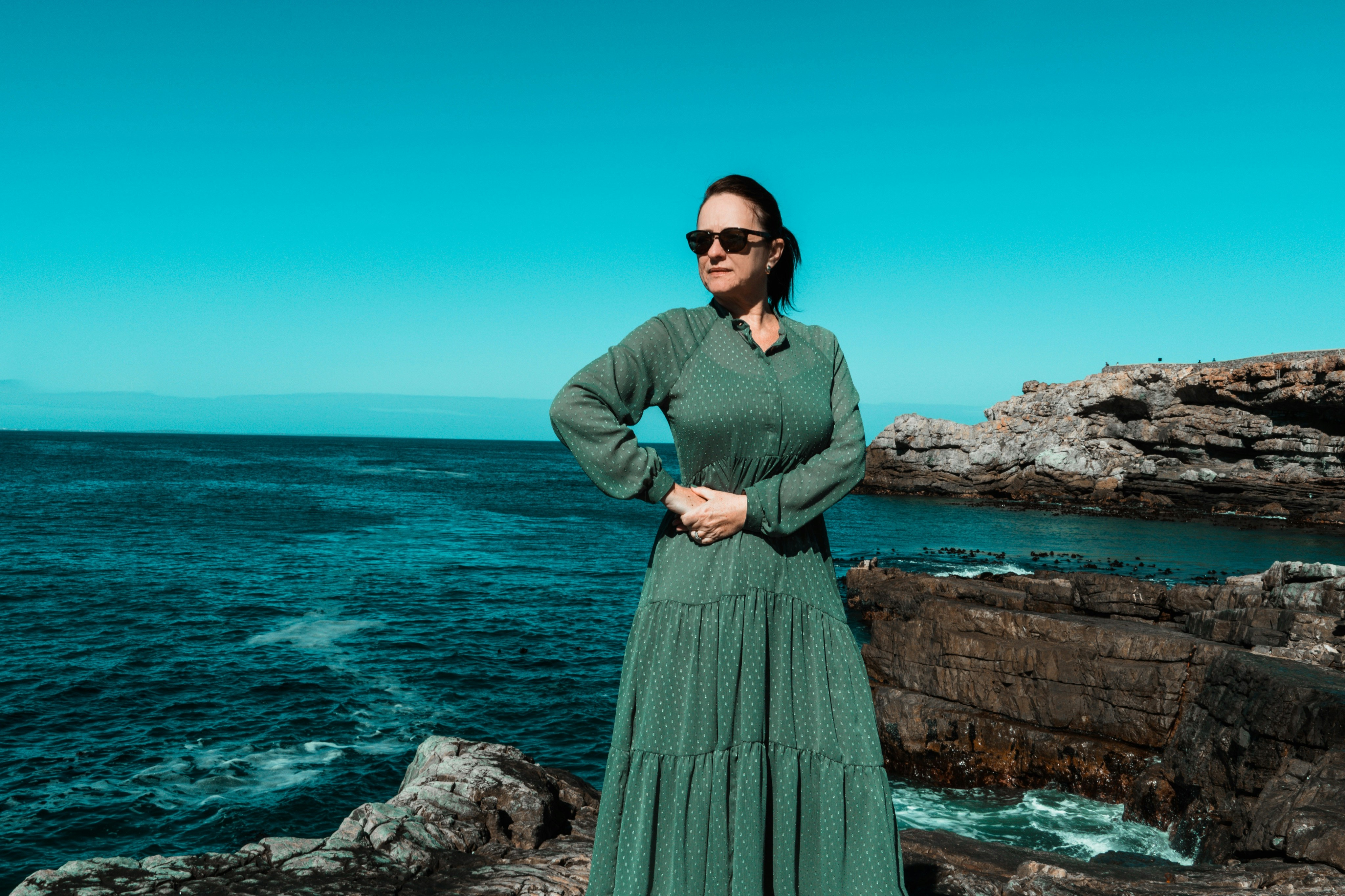Woman standing outdoors wearing a long-sleeved green maxi dress offering full coverage.