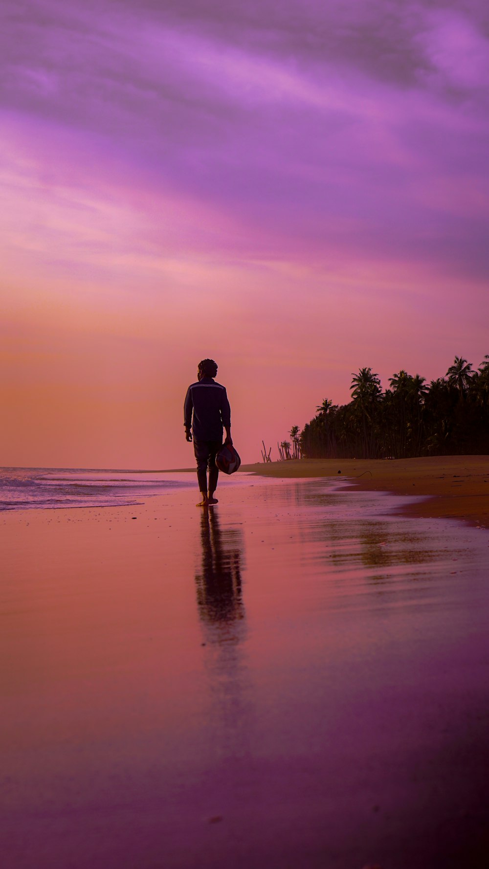 man in black jacket walking on beach during sunset