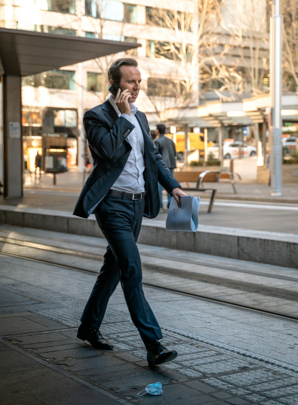 man in black leather jacket and blue denim jeans standing on sidewalk during daytime