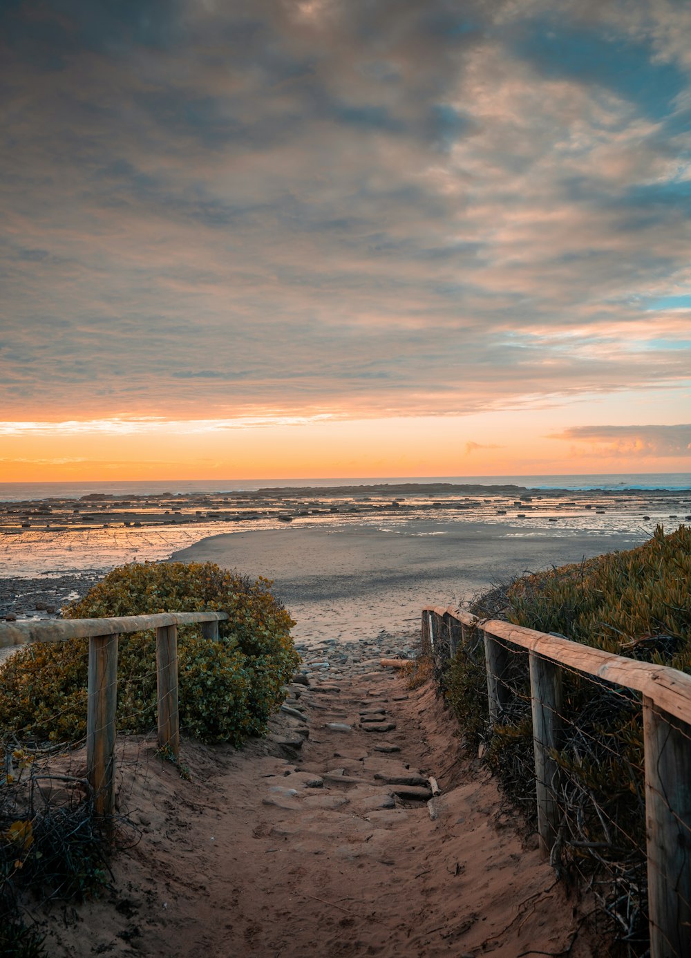 a wooden bench sitting on top of a sandy beach