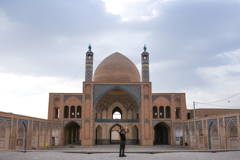 man in black jacket walking near brown concrete building during daytime