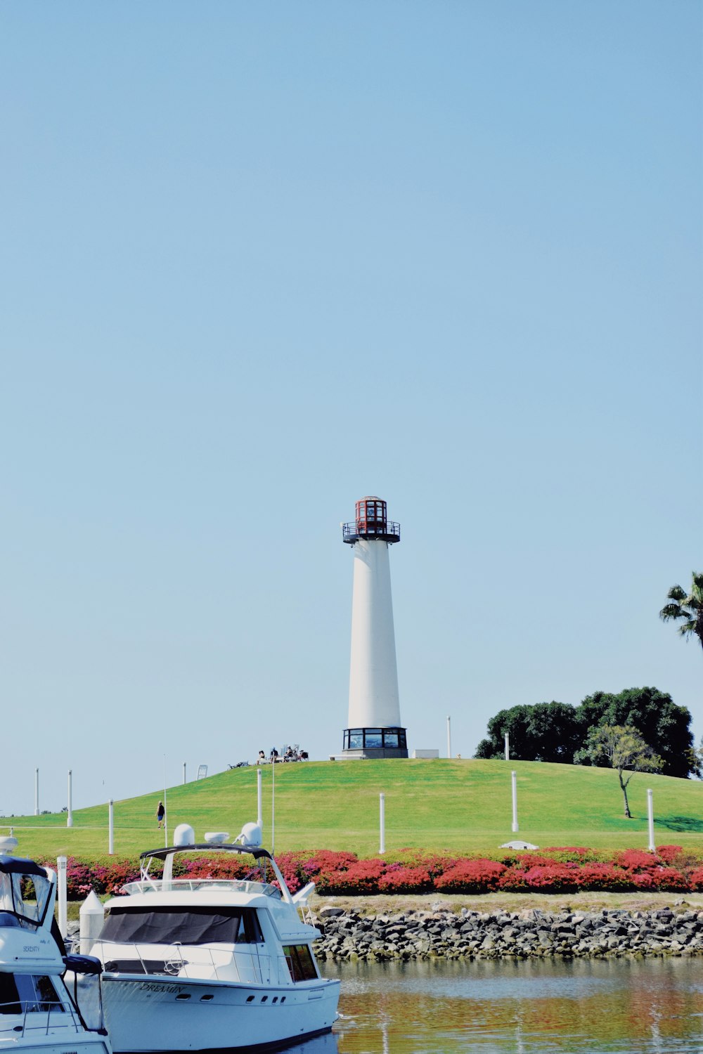 white and black lighthouse on green grass field under blue sky during daytime