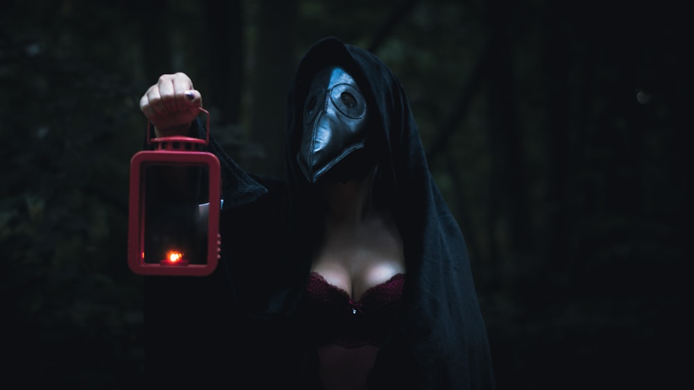 赤と黒のスマートフォンを持つ黒いパーカーの女性