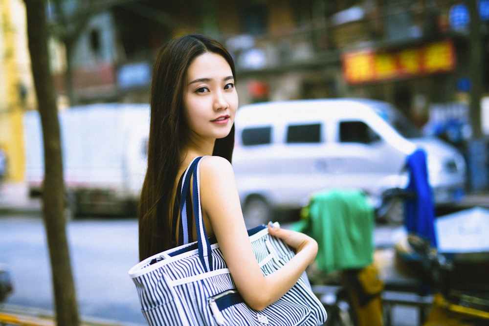 woman in black and white stripe tank top holding white basket