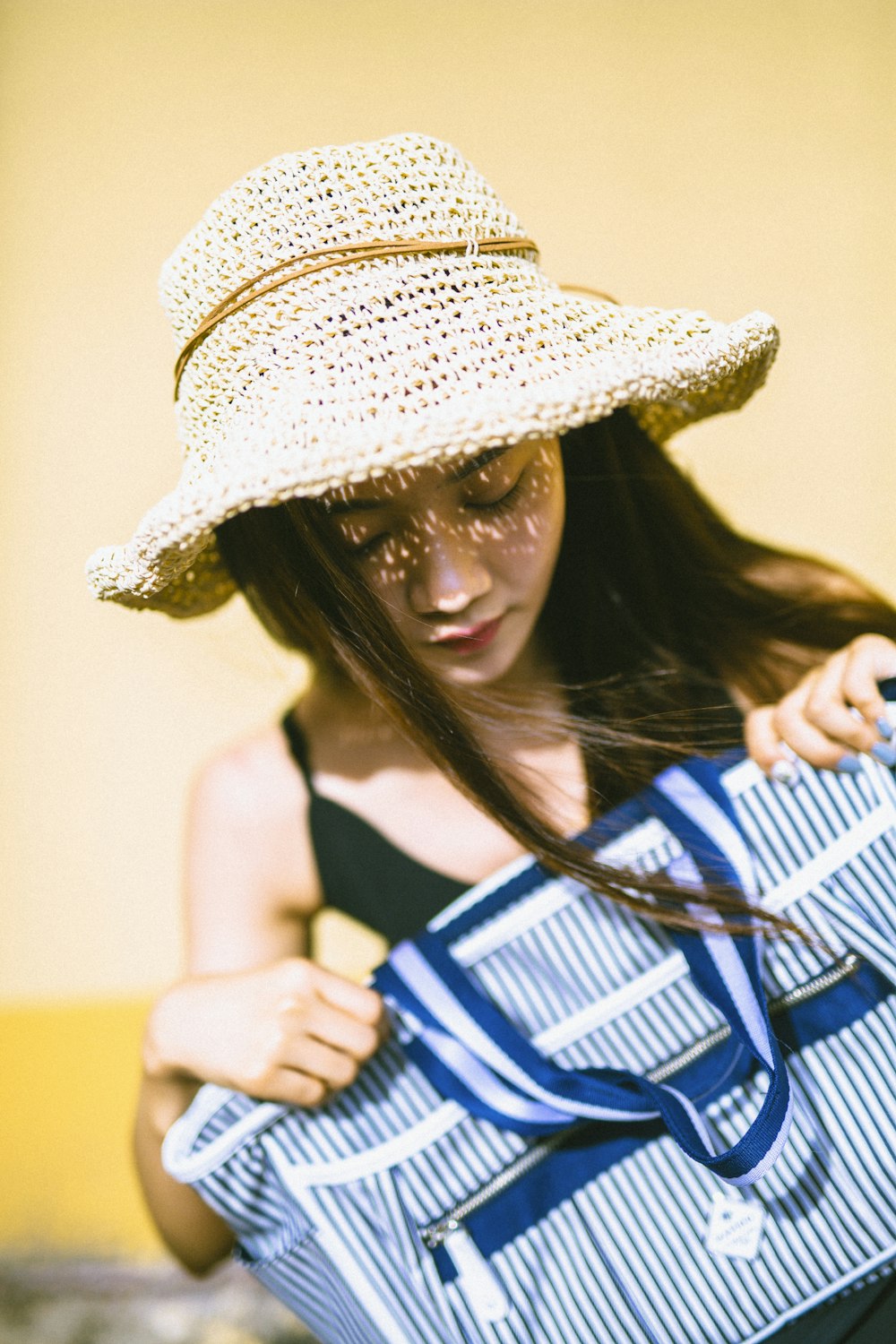 woman in white and blue stripe tank top wearing brown straw hat