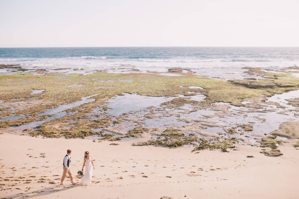 2 women walking on beach during daytime