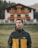boy in black and orange jacket standing on green grass field during daytime