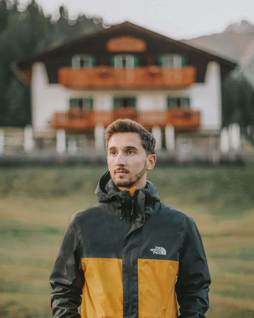 boy in black and orange jacket standing on green grass field during daytime