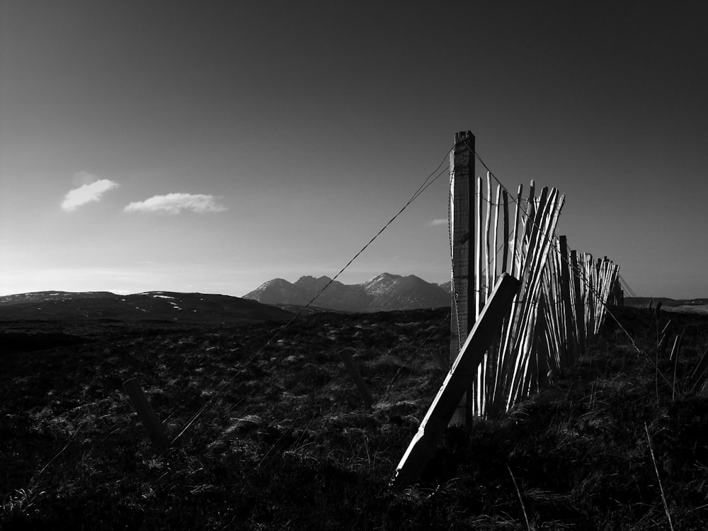 grayscale photo of wooden fence on grass field