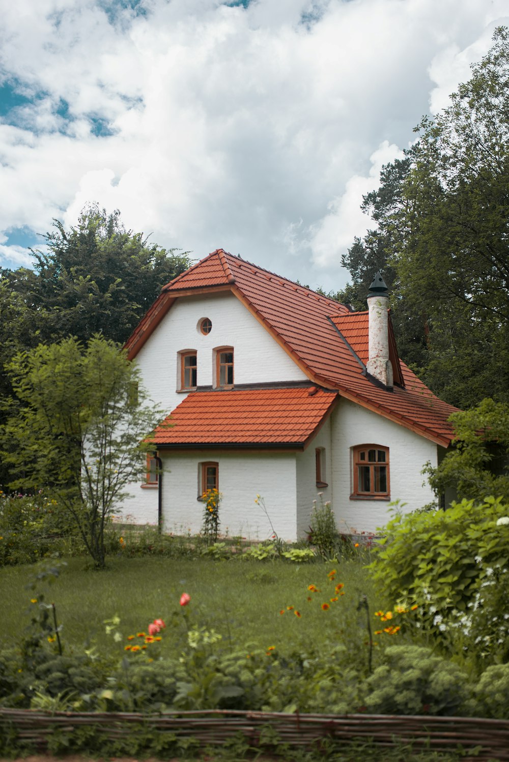 white and brown concrete house near green trees under white clouds during daytime