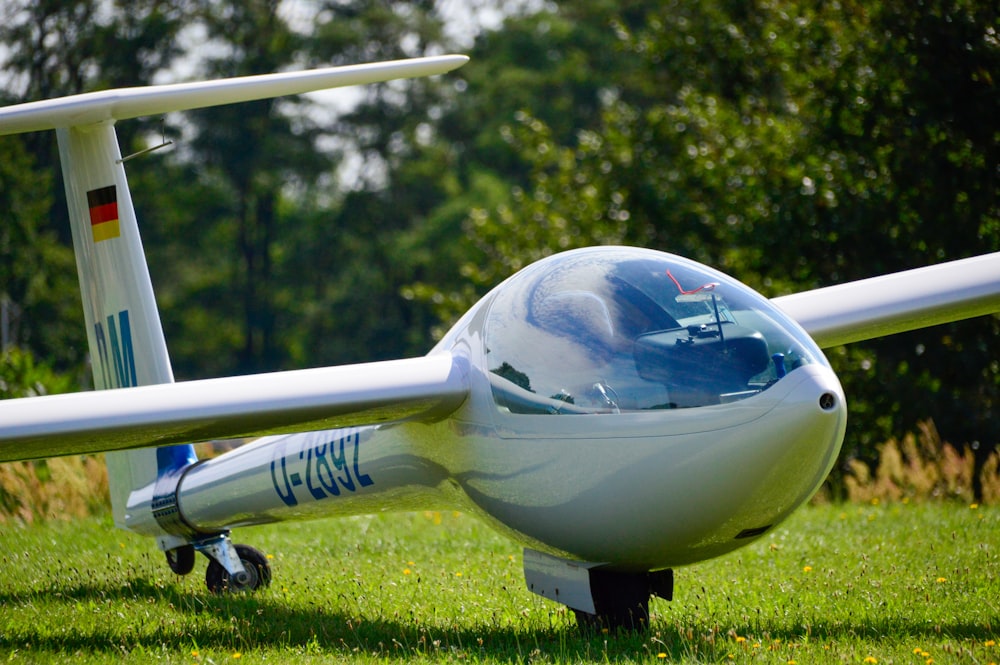 white and blue airplane on green grass field during daytime