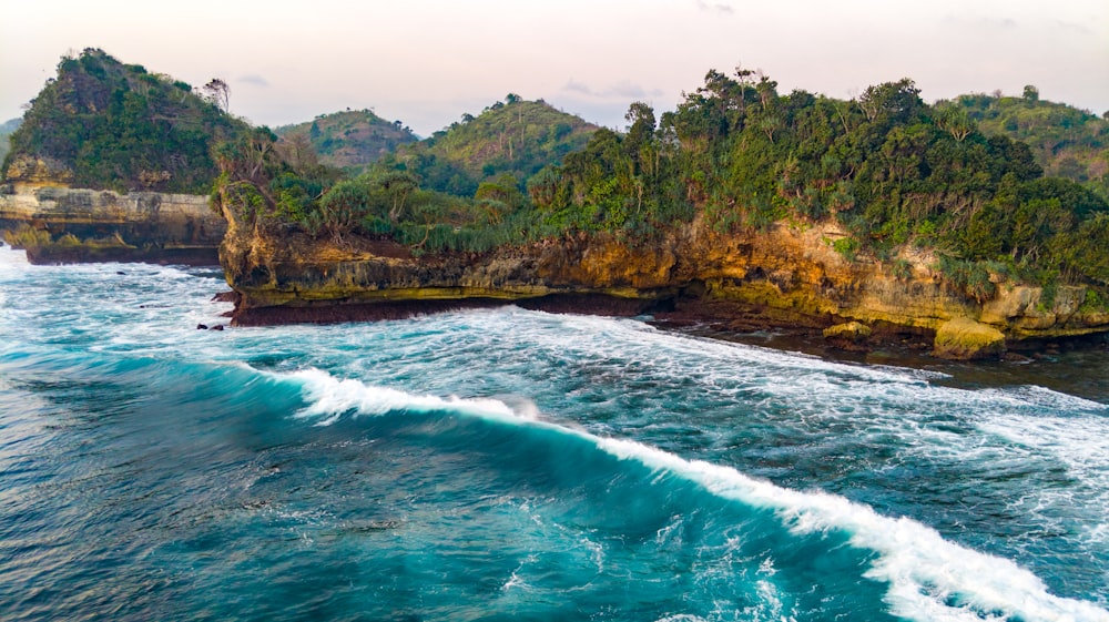 Montaña verde y marrón al lado del cuerpo de agua durante el día