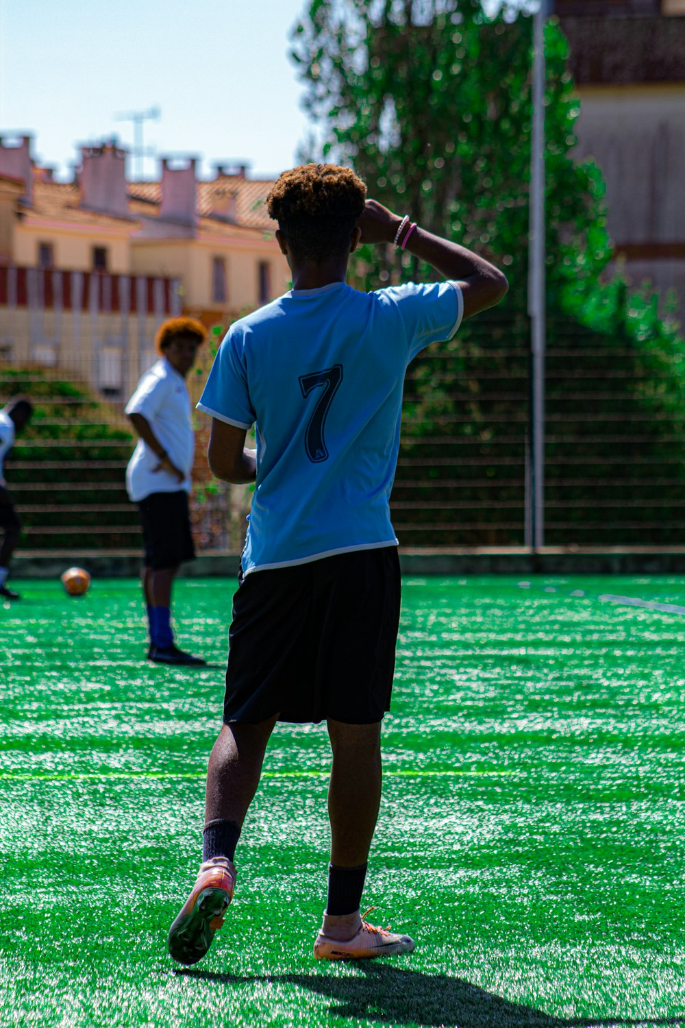 man in white and blue nike soccer jersey shirt and black shorts standing on green field