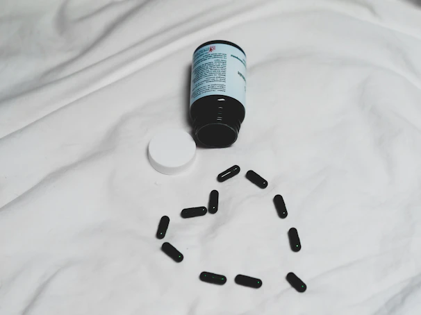 Orygenes tablets spilling elegantly from a sleek black container on a nightstand.