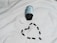 A black bottle of pills is lying on its side on a white surface, with its white cap detached. Several black capsules are arranged in the shape of a heart below the bottle.
