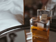 Perfume bottle resting on a bed of white silk fabric, reflecting soft light.