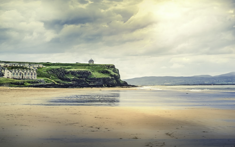 green and brown rock formation on sea shore under white clouds during daytime