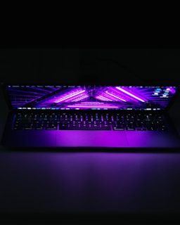 A sleek laptop emitting digital streams in purple and black tones