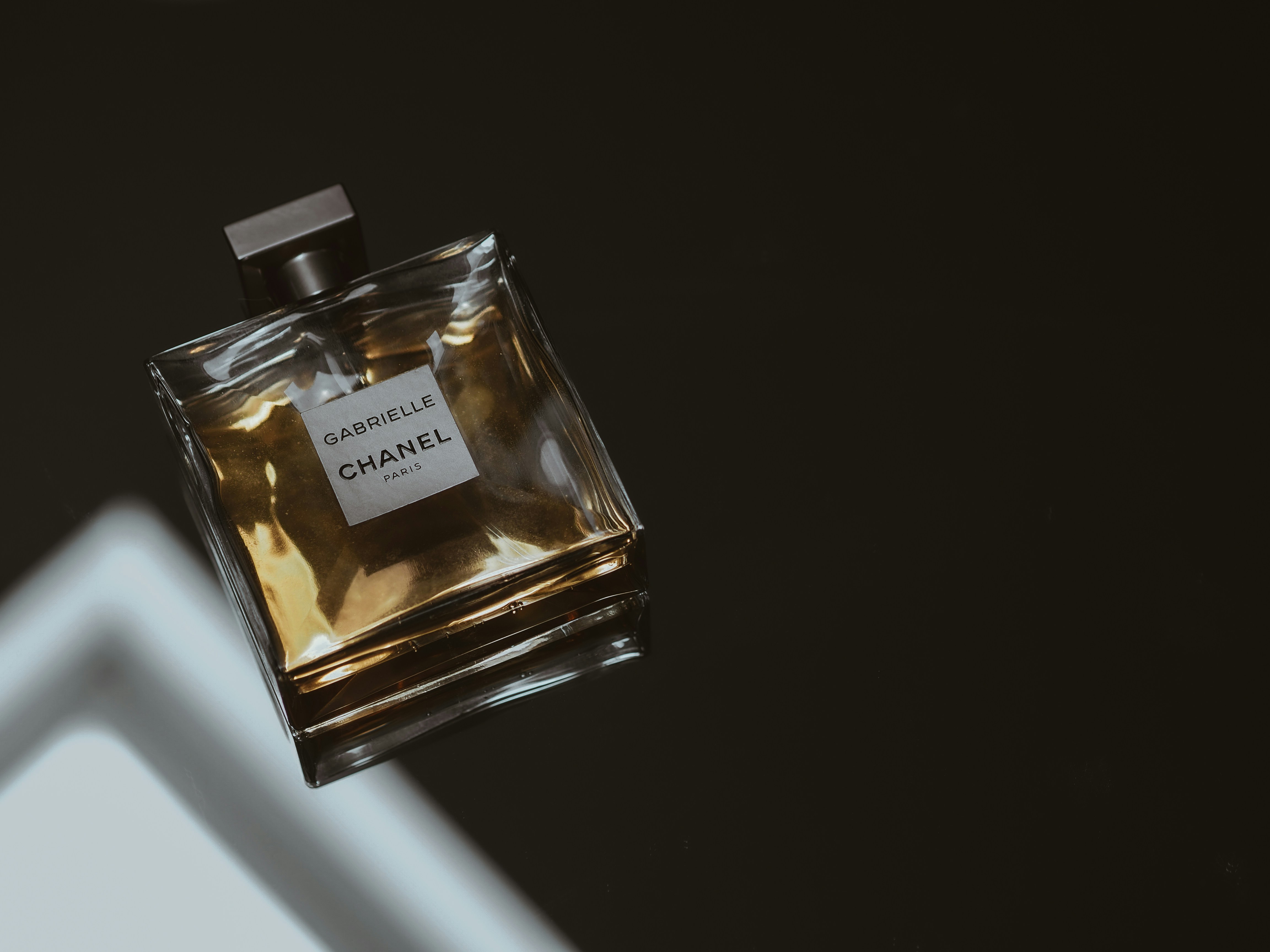 Luxury perfume bottle with dramatic side lighting showing glass clarity and golden liquid inside
