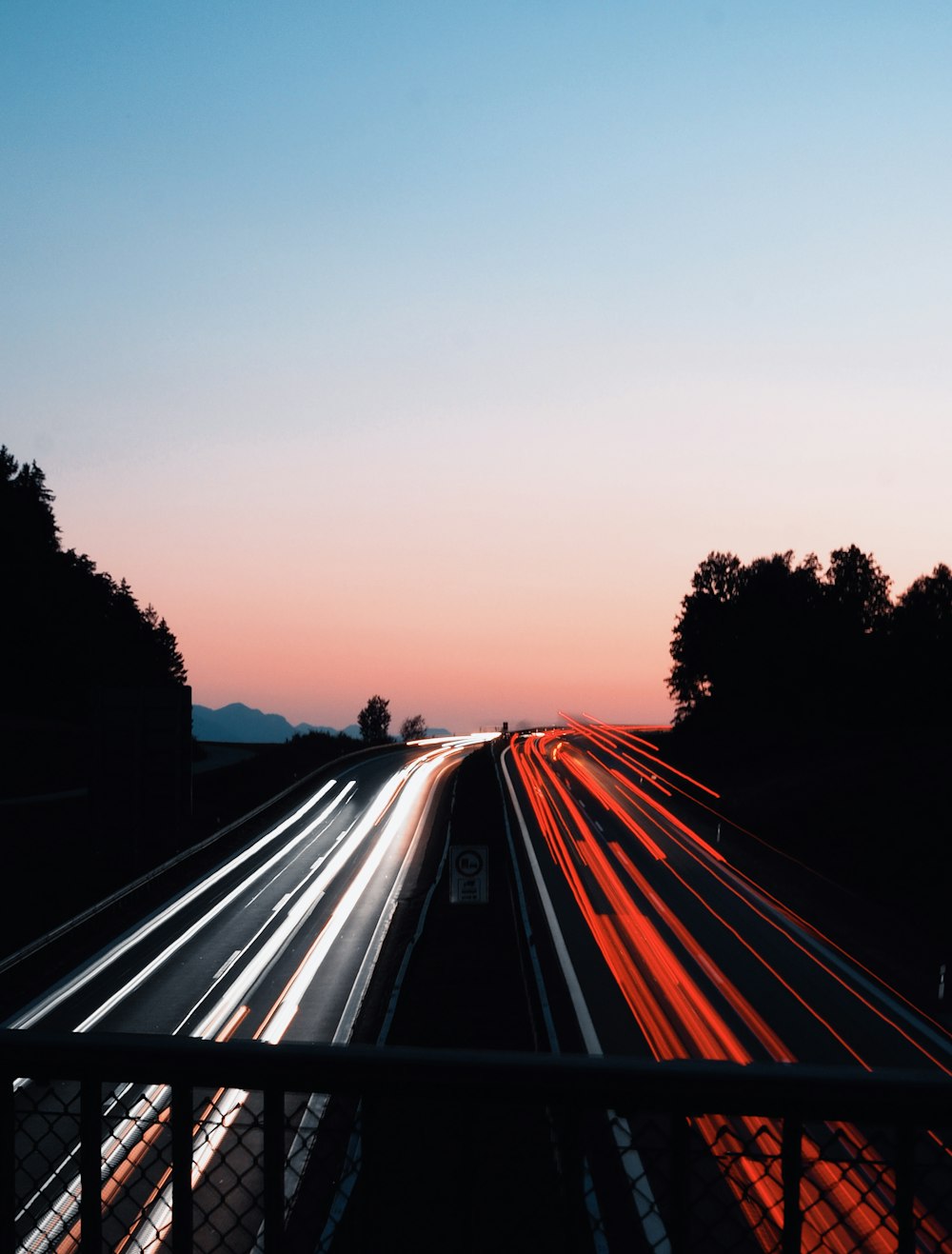 Fotografía de lapso de tiempo de automóviles en la carretera durante la puesta del sol