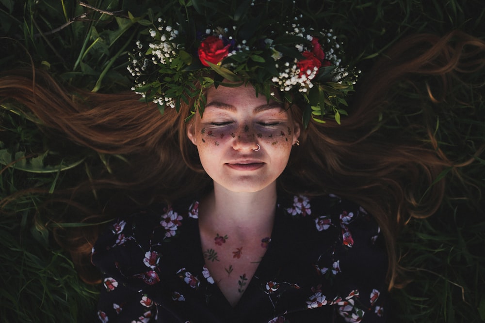 woman in black and pink floral shirt with red flower on head