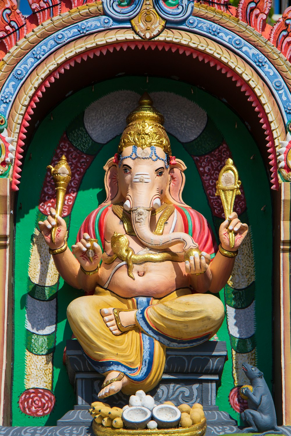 estatua de la deidad hindú de oro en tela verde y roja