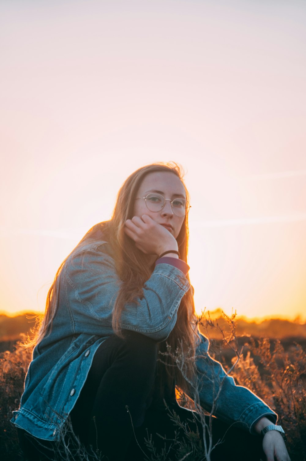 woman in blue denim jacket standing on brown field during daytime